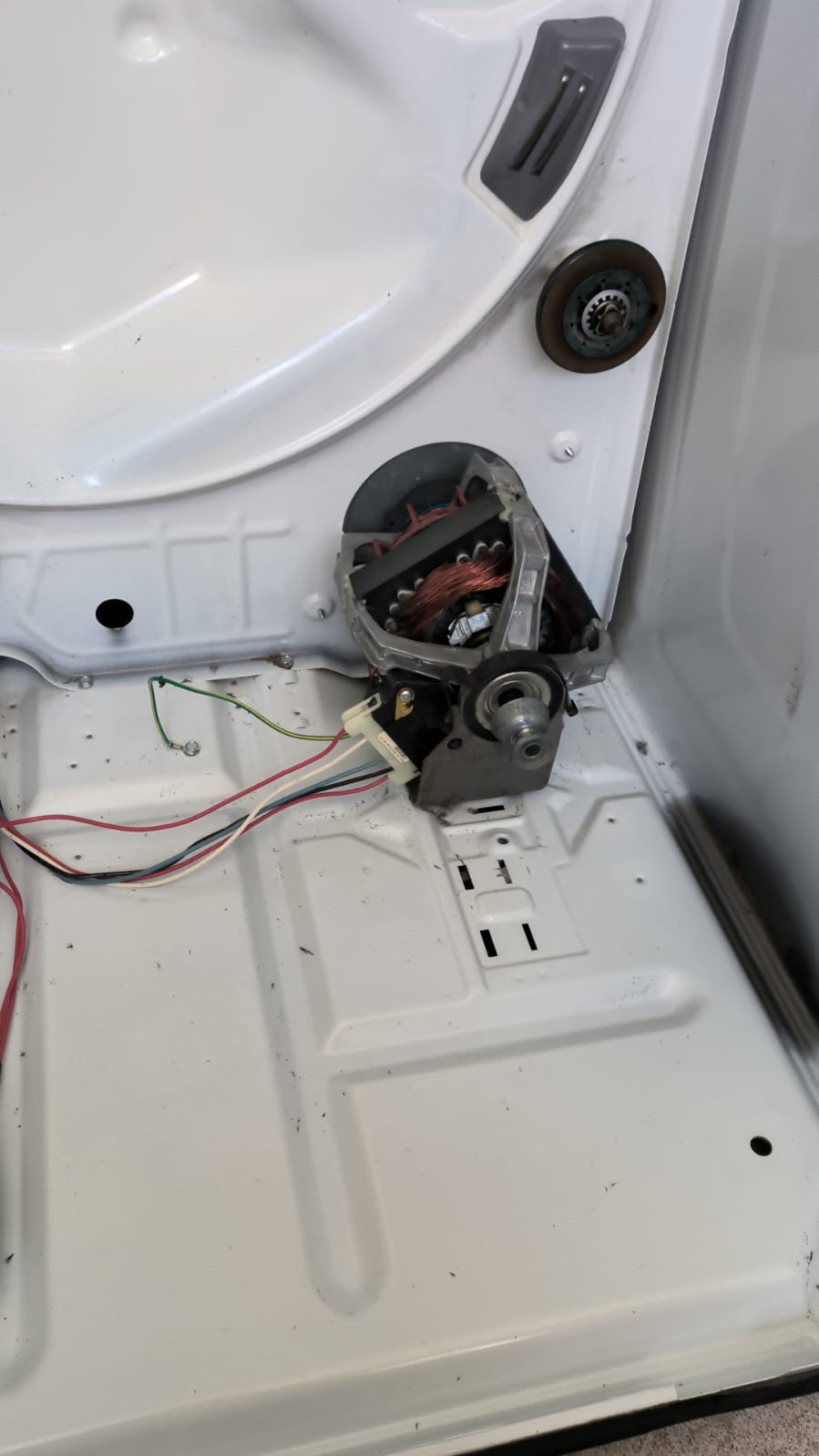 Interior de la misma secadora limpio, con motor y base sin pelusa después del mantenimiento