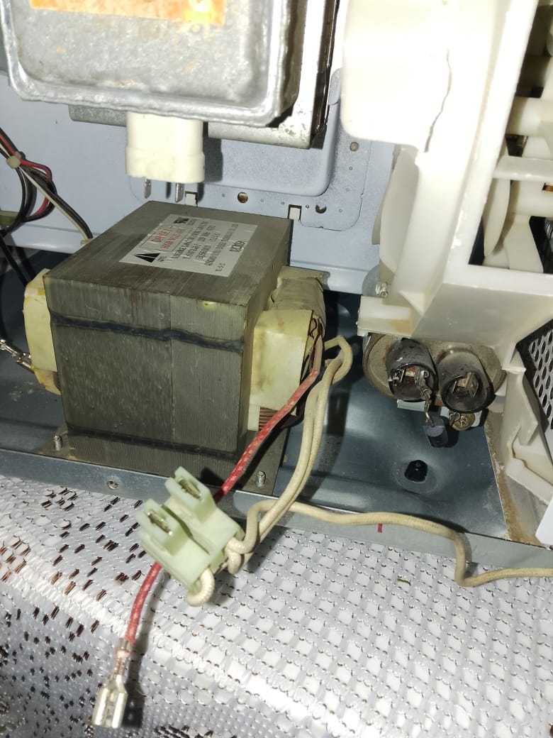 Transformador de alto voltaje y conexiones internas del microondas durante la reparación
